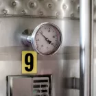 Termômetro acoplado a tanque industrial de aço inox representando instrumentos usados para evitar os erros de medição de vazão.